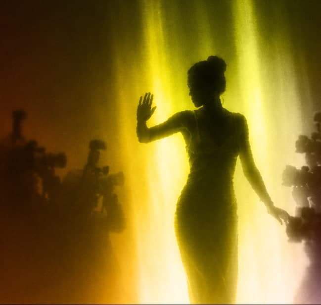 Creator in the spotlight waving before a bank of press cameras, representing influencer marketing campaign reach